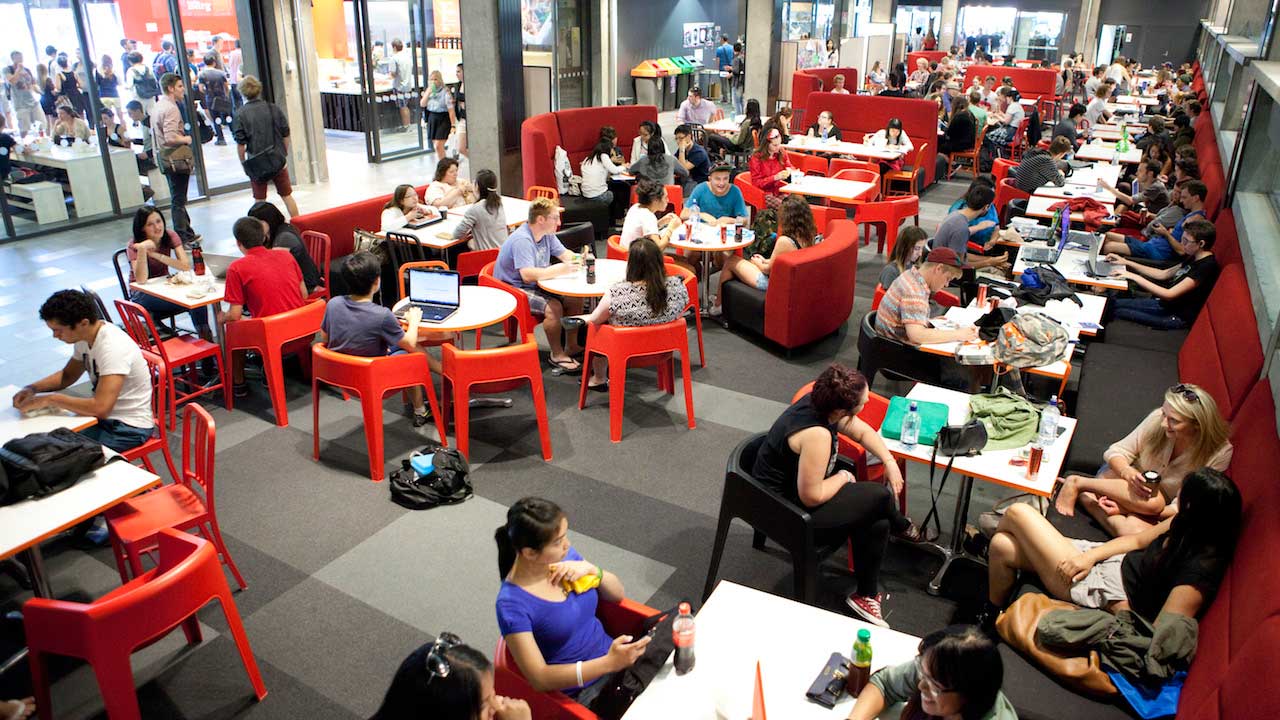 Students sit at tables in a dining hall on University of Canterbury's campus