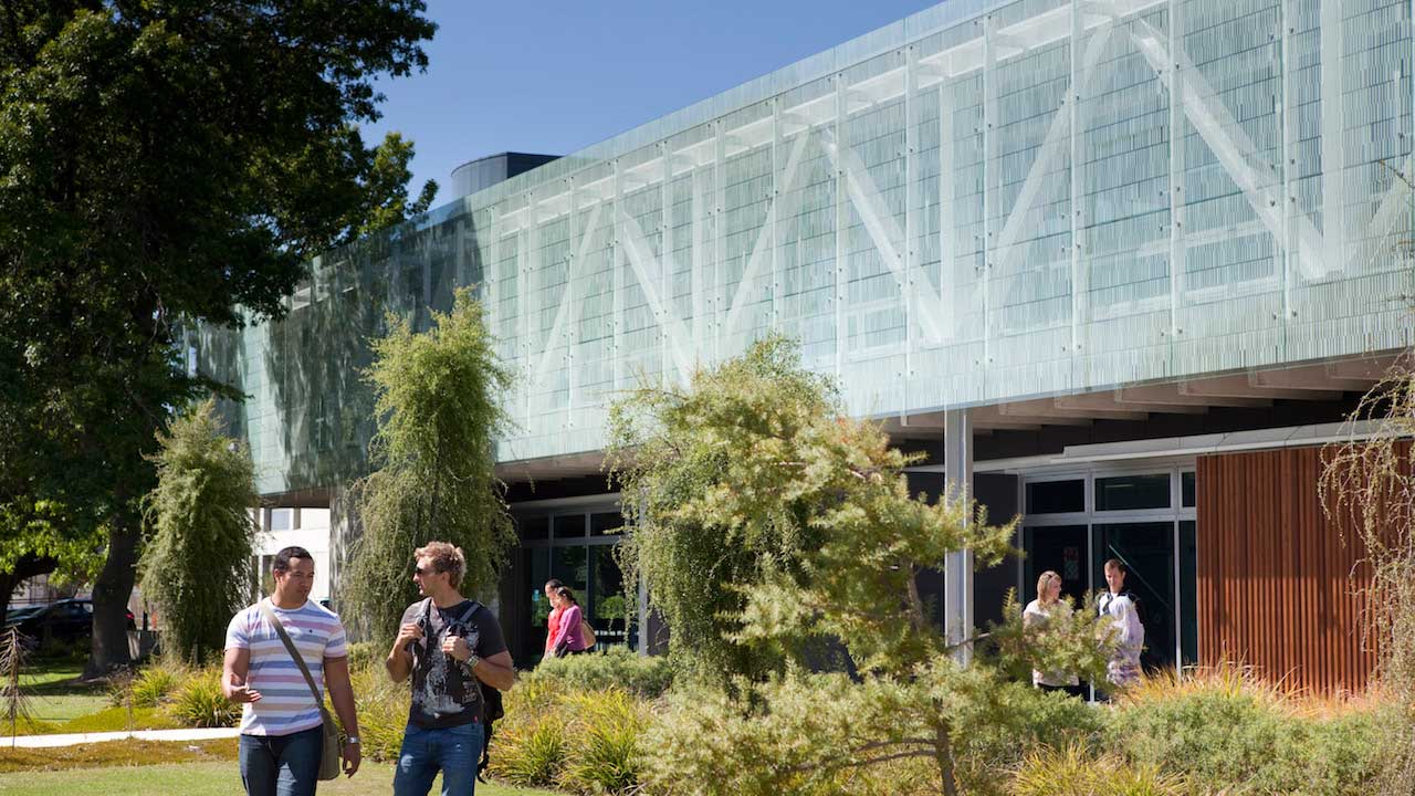 Two men converse and walk on University of Canterbury's campus