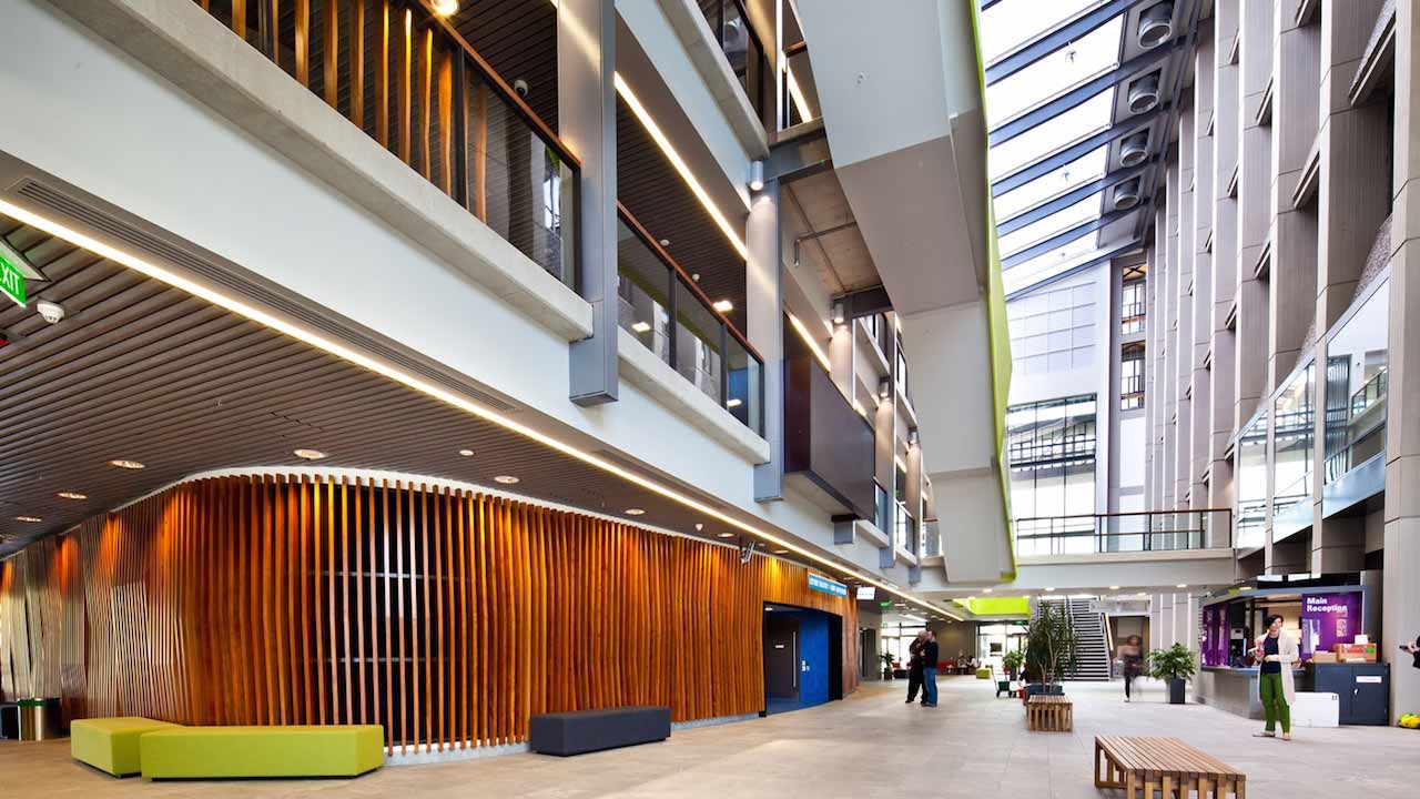 People walk along the bottom floor of a modern building on University of Auckland's campus
