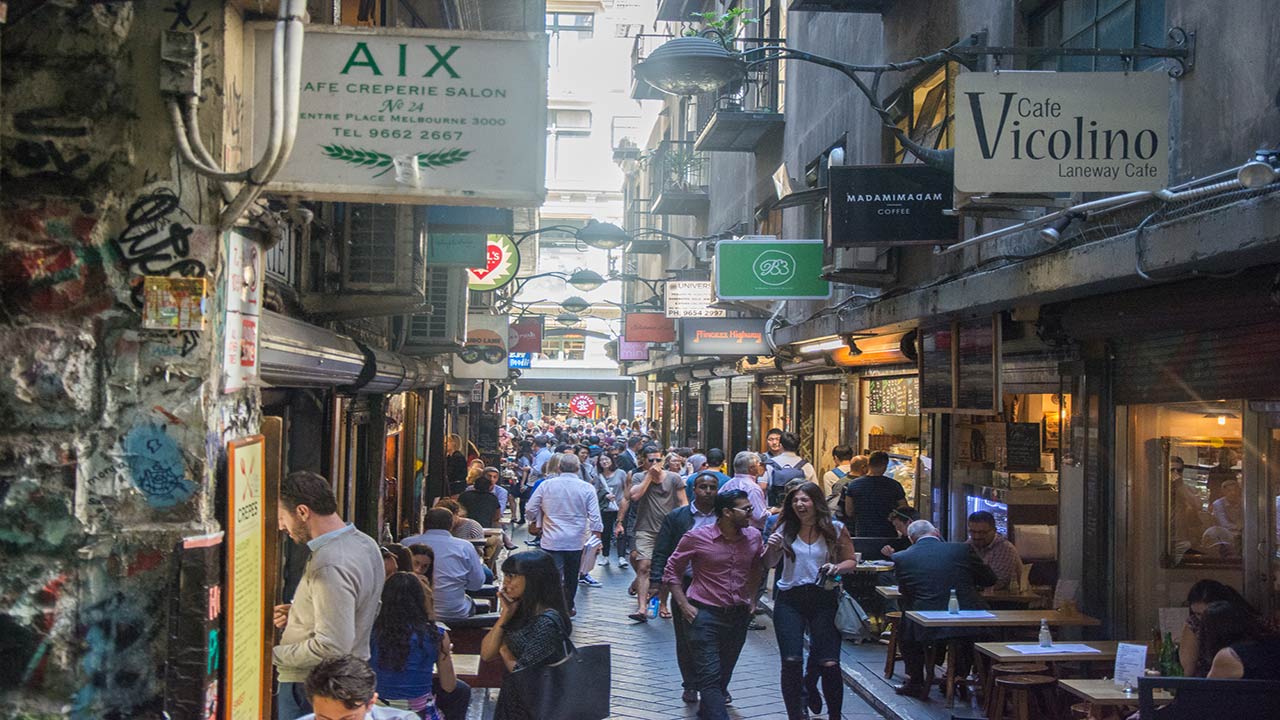 A crowded laneway lined with restaurants and shops in downtown Melbourne