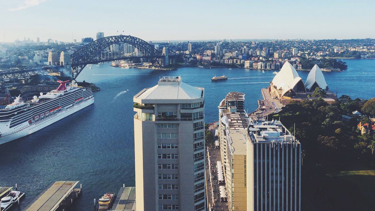 Sunny cityscape of Sydney, featuring the infamous Sydney Harbour Bridge and Sydney Opera House
