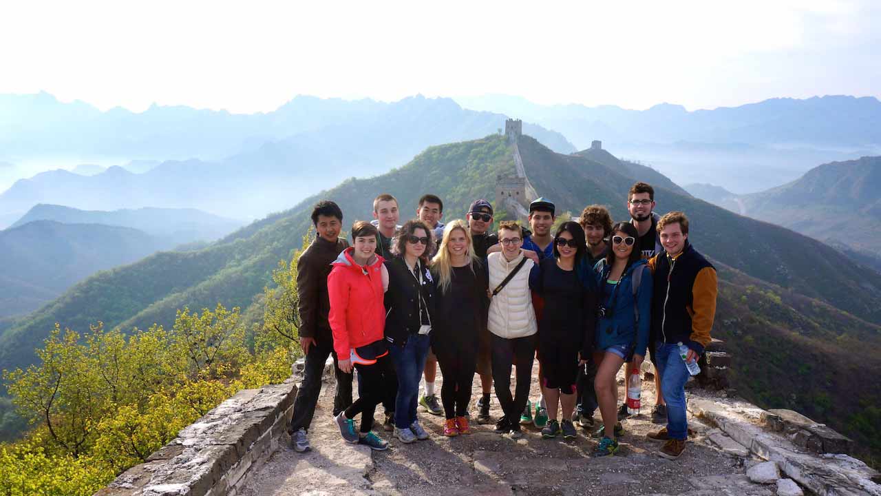 A group of students stand together smiling on the Great Wall of China