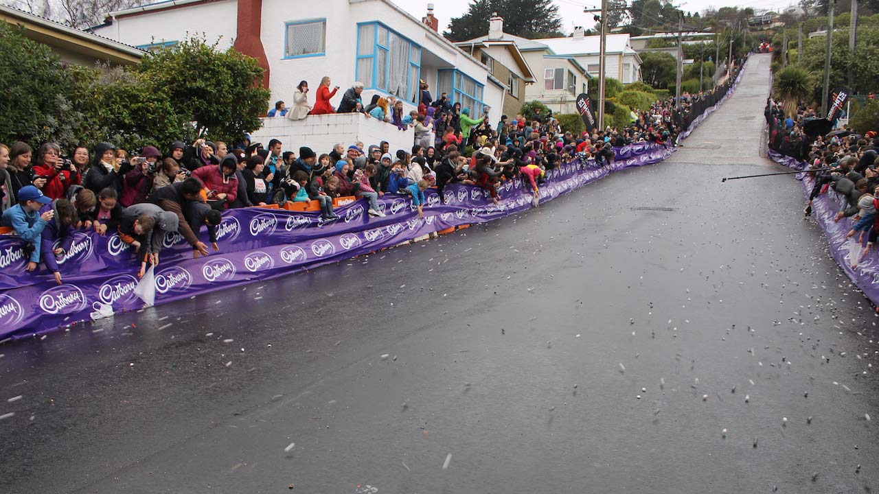 Crowds gather on the sidewalk to watch an upcoming marathon in Dunedin, New Zealand
