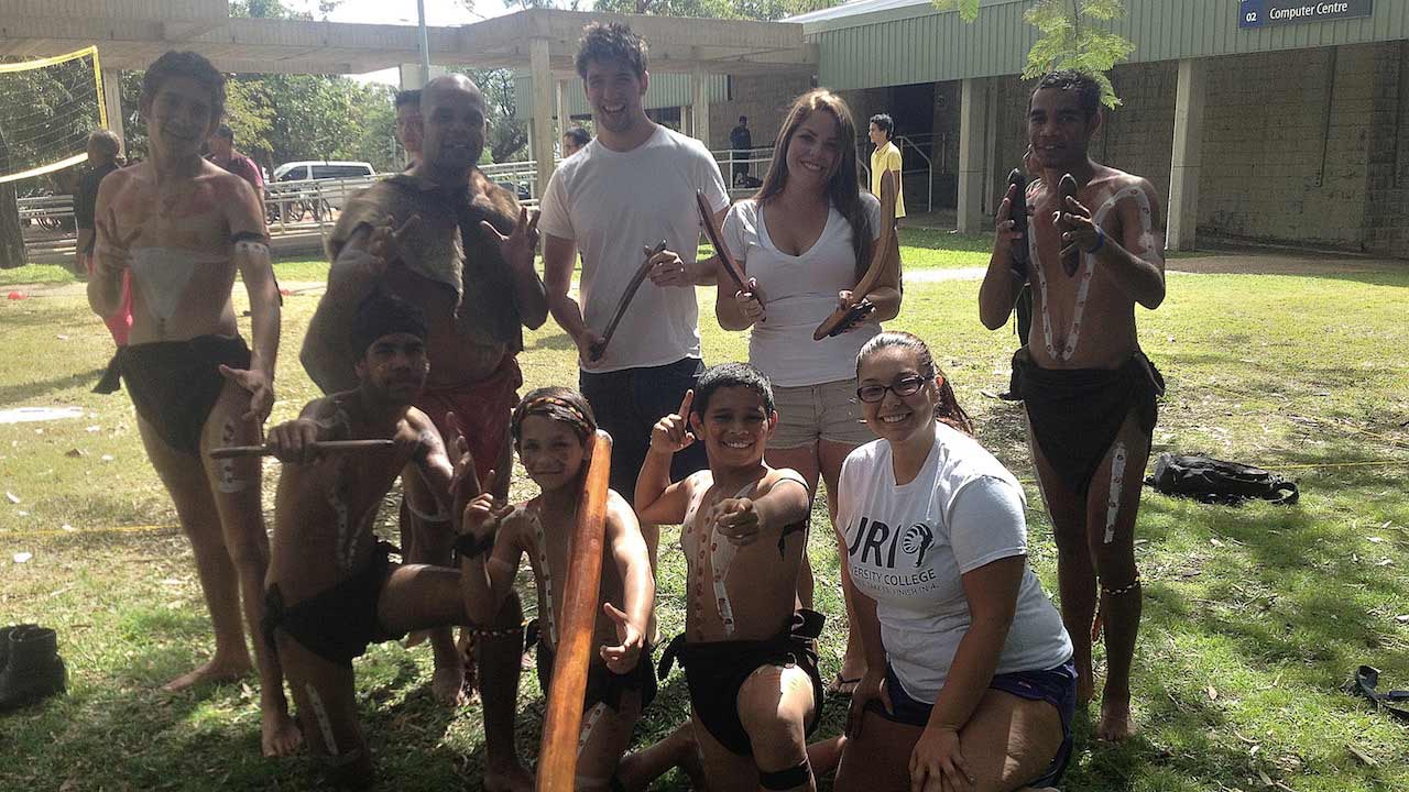 Students pose with aboriginal men wearing traditional clothes in Townsville, Australia