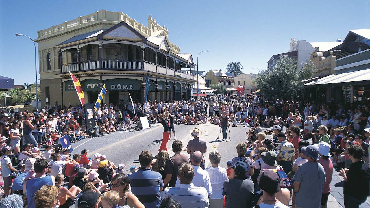 A crowd circles around street performers on the street in Perth, Australia