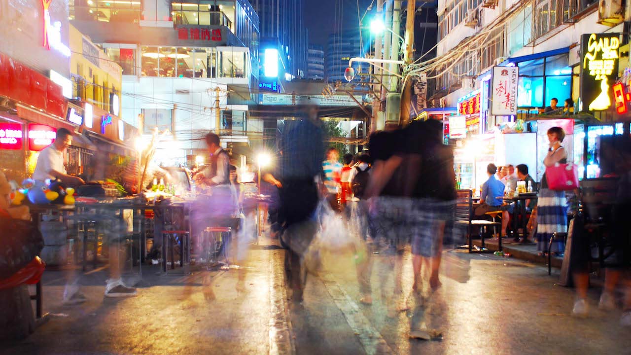 Blurred motion of people walking a brightly lit and bustling street in Shanghai at night