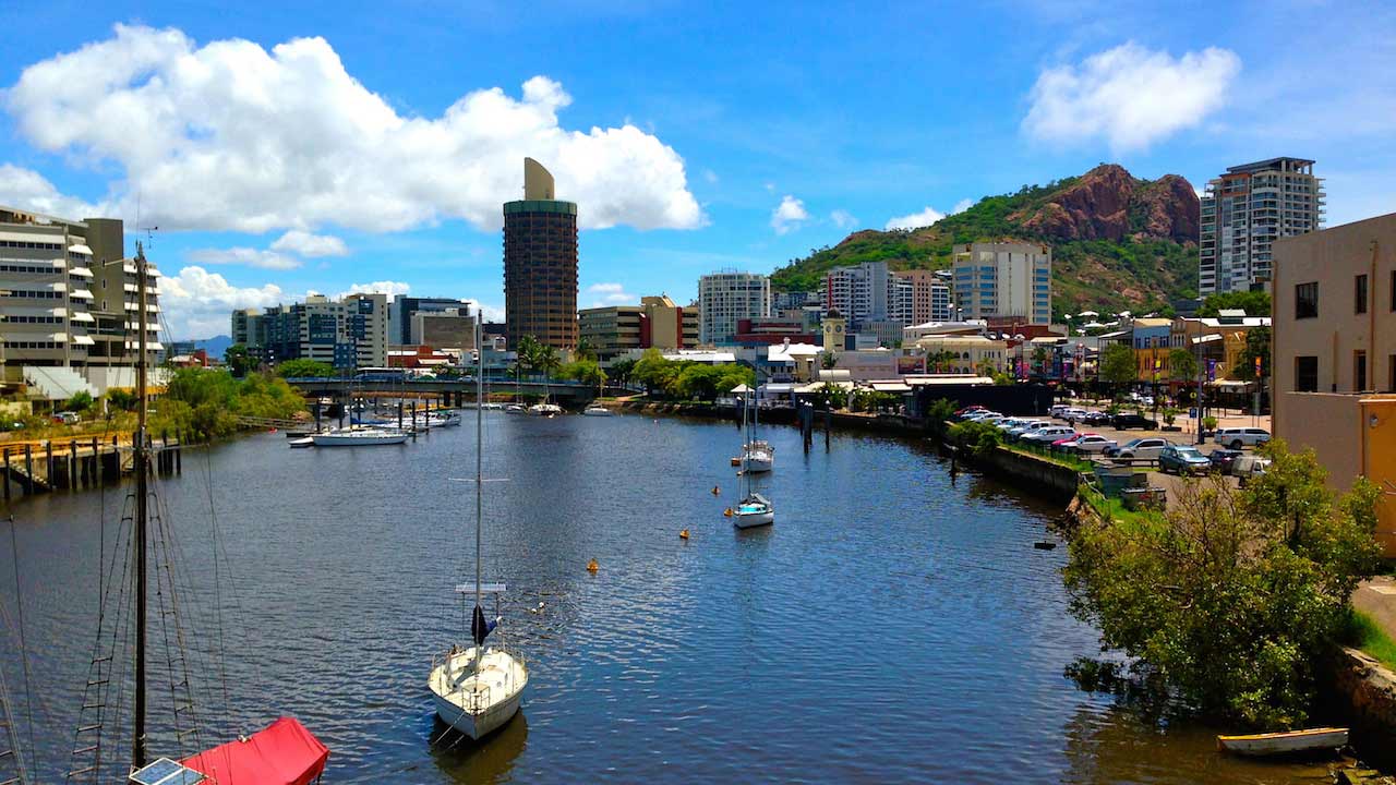Boats cruise along the canal lined with buildings in Townsville, Australia