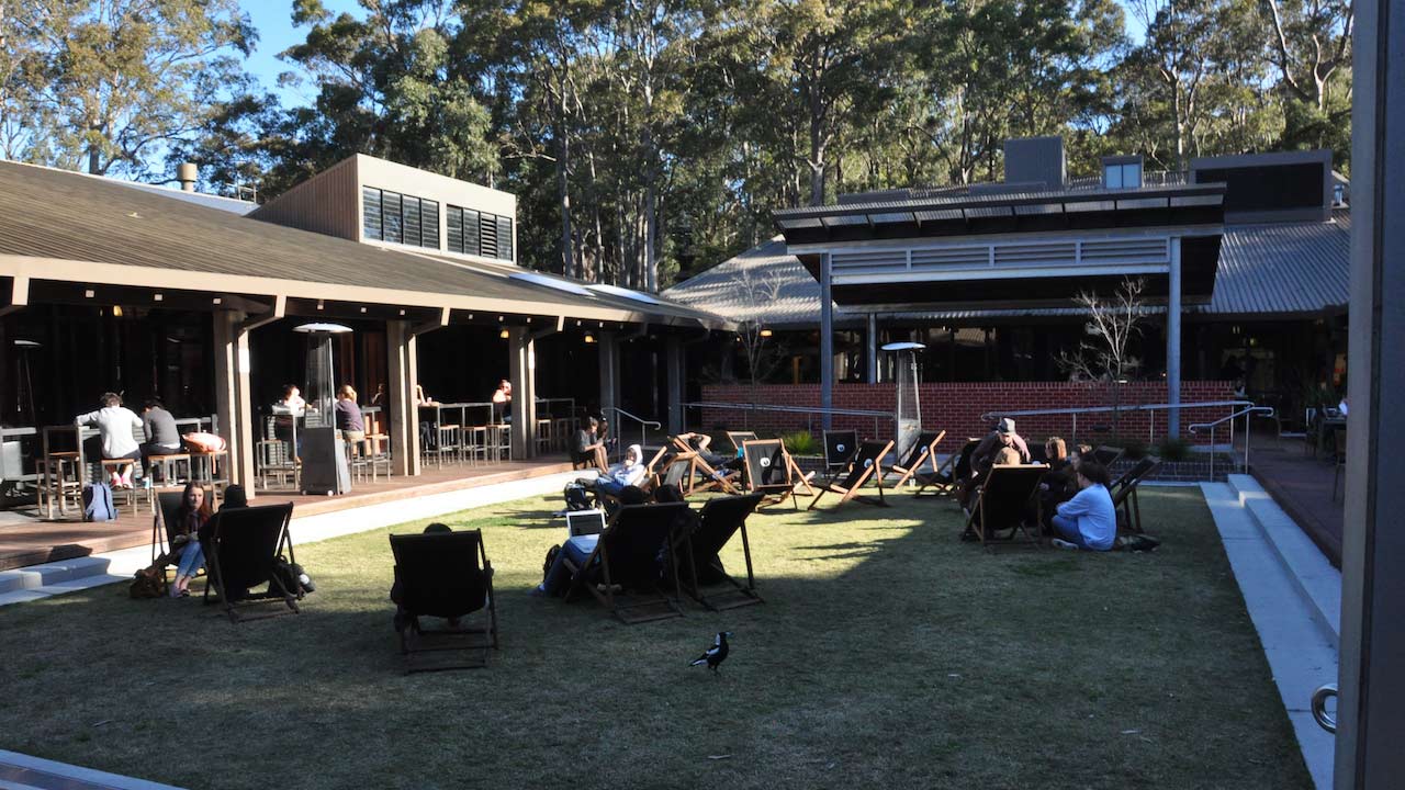 People sit in lawn chairs scattered about the student center's quad on University of Newcastle's campus
