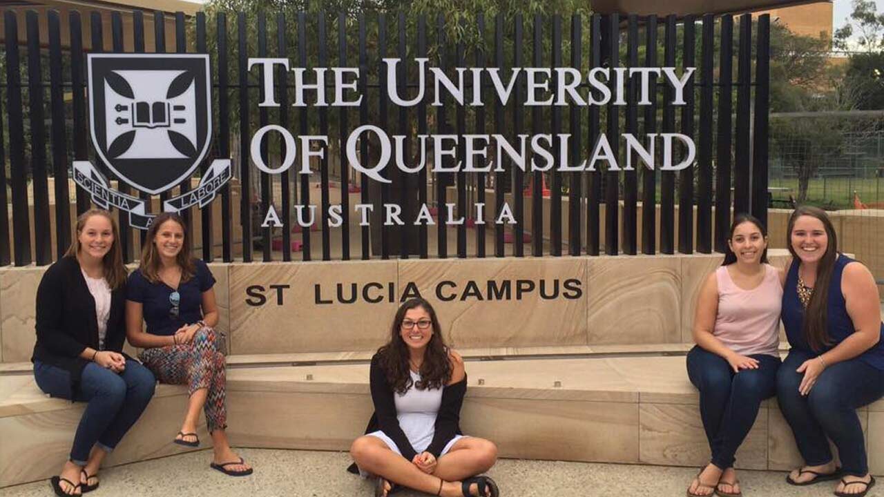 Five female students pose beside the 'University of Queensland, St. Lucia Campus' sign