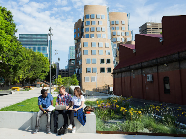 Three people sit on a bench on UTS's campus