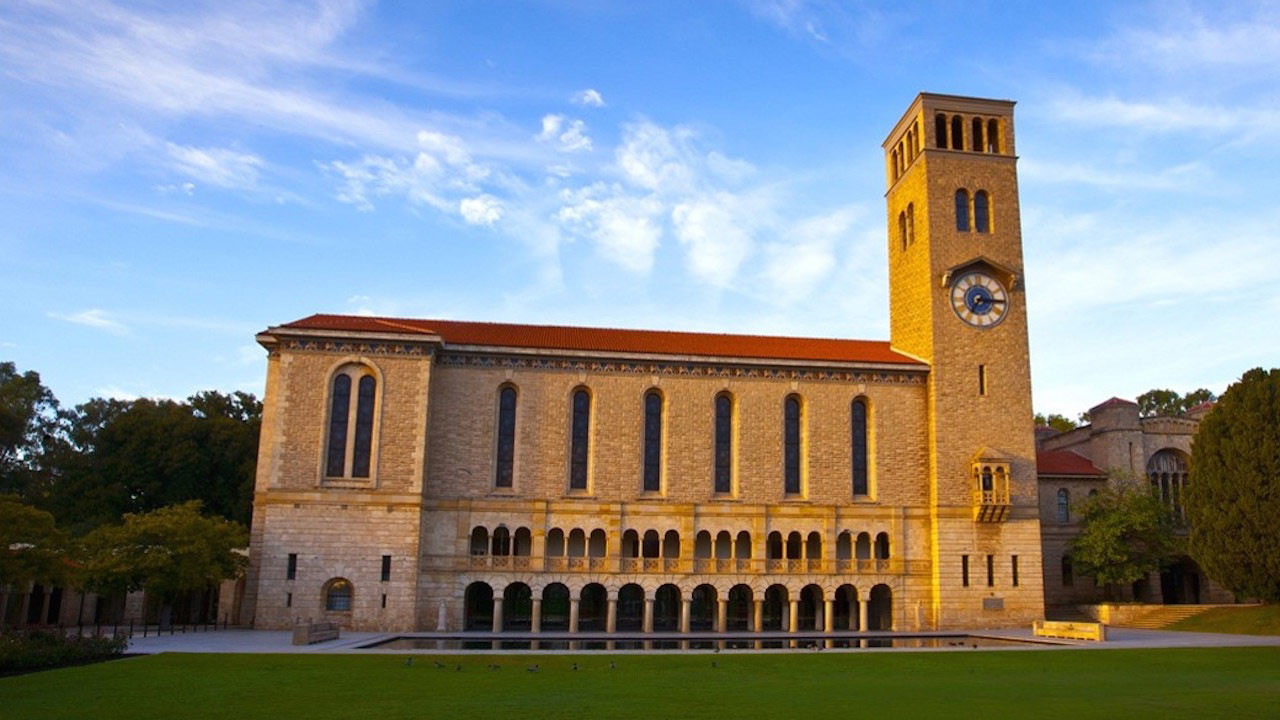 An ornate brick building stands near a grassy quad basking in golden sunlight on University of Western Australia's campus in Perth