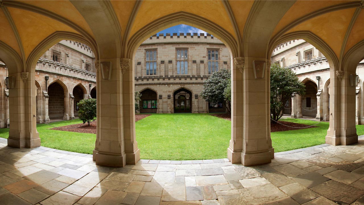 A vibrant green quad surrounded by a medieval-like corridor at University of Melbourne