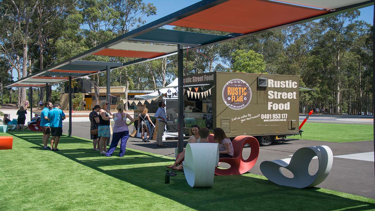 People gather outside a food truck on University of Newcastle's campus on a sunny day