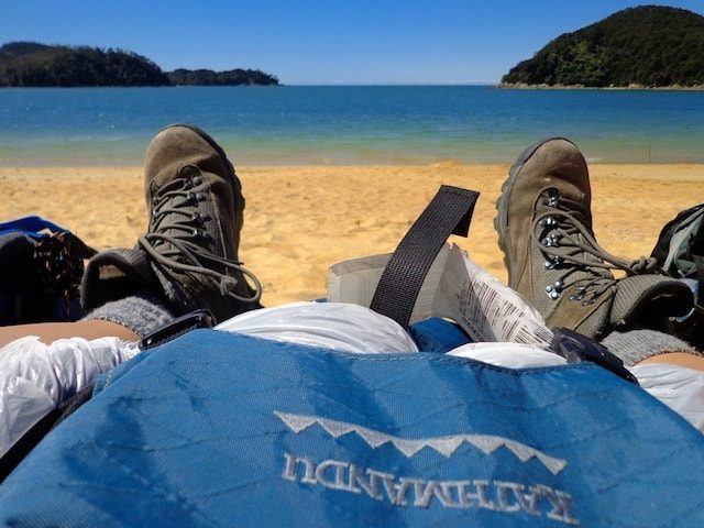 Hiking boots and backpack resting on a beach in New Zealand